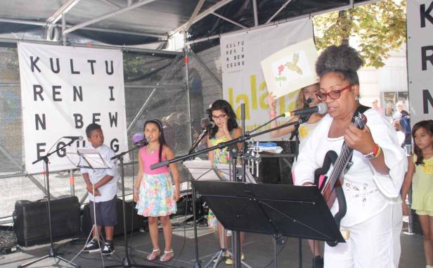 Eine Gruppe von Kindern und eine Frau treten auf einer Bühne auf.