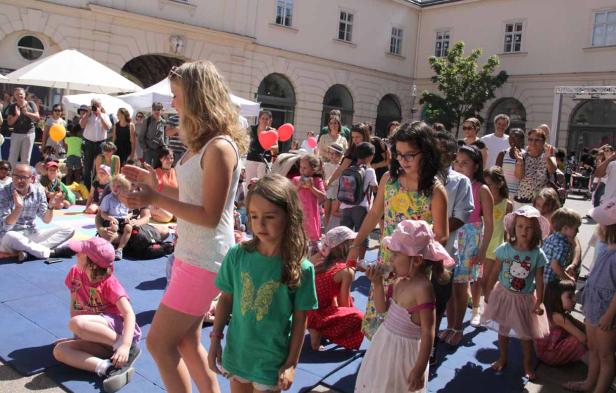 Eine Gruppe von Kindern und Erwachsenen versammelt sich im Freien für eine Veranstaltung.