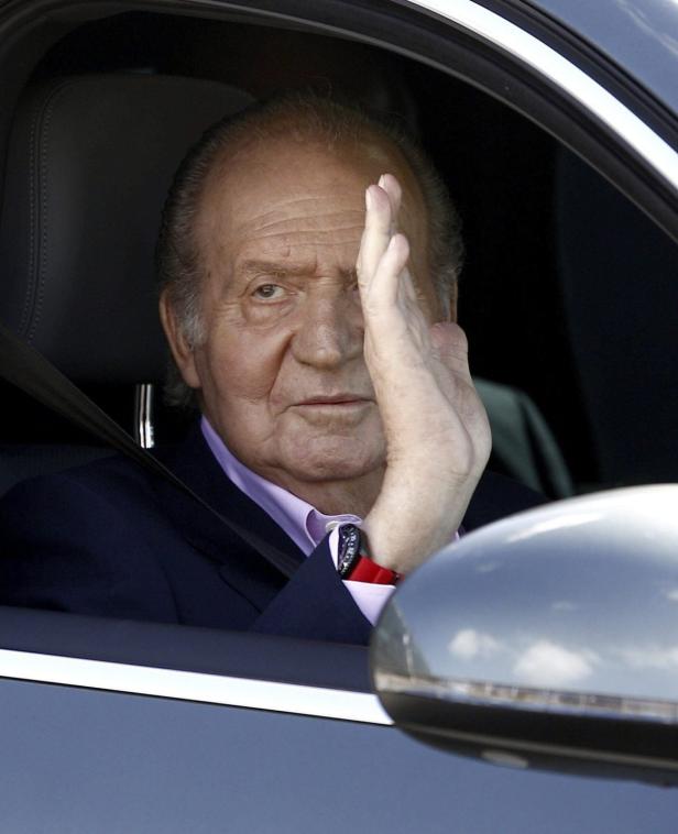Juan Carlos I. sitzt in einem Auto und schützt sich mit der Hand vor der Sonne.