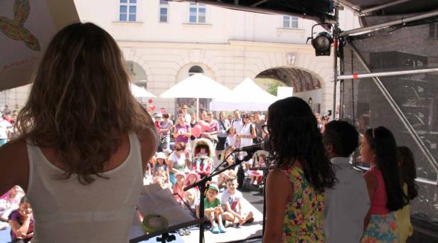 Eine Frau steht auf einer Bühne vor einem Publikum aus Kindern und Erwachsenen.
