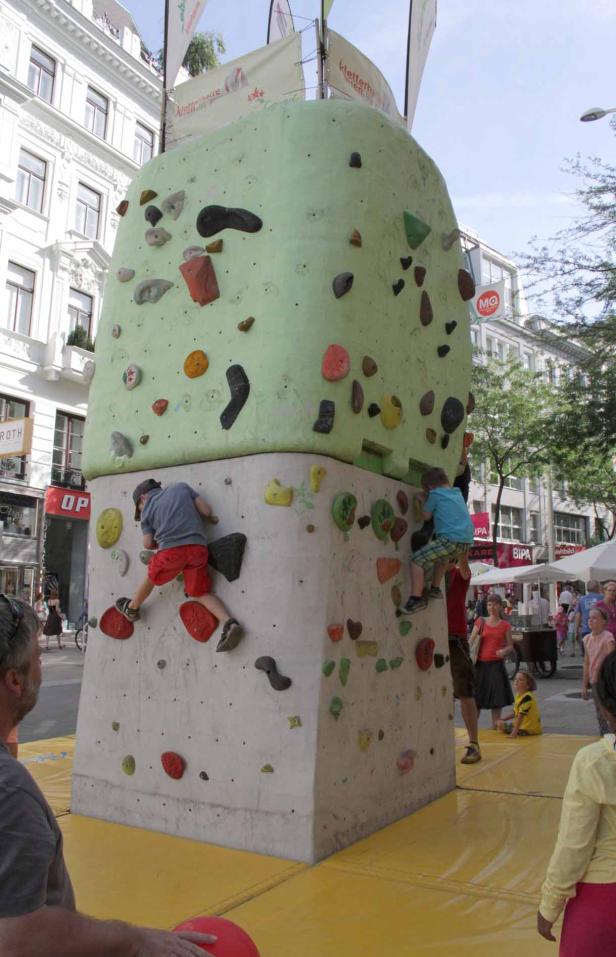 Zwei Kinder klettern an einem Kletterturm im Freien.