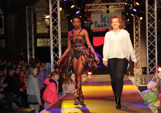 Zwei Models präsentieren Mode auf einem Laufsteg vor Publikum.
