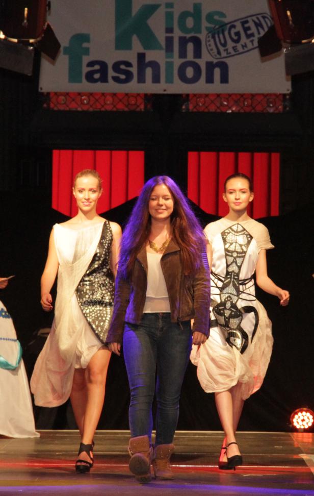 Drei junge Frauen präsentieren Mode auf einer Bühne bei „Kids in Fashion“.