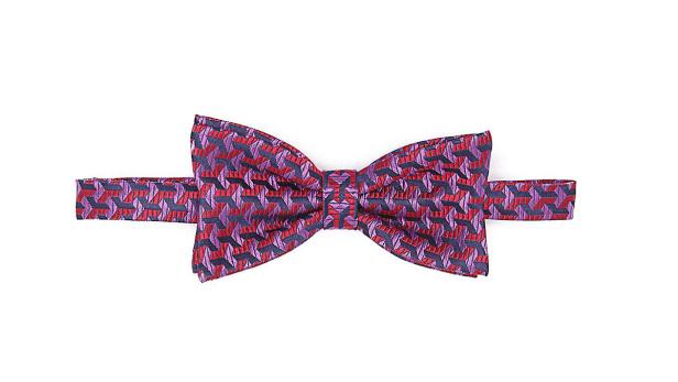 Eine gemusterte Fliege in Rot-, Lila- und Blautönen liegt auf einem weißen Hintergrund.