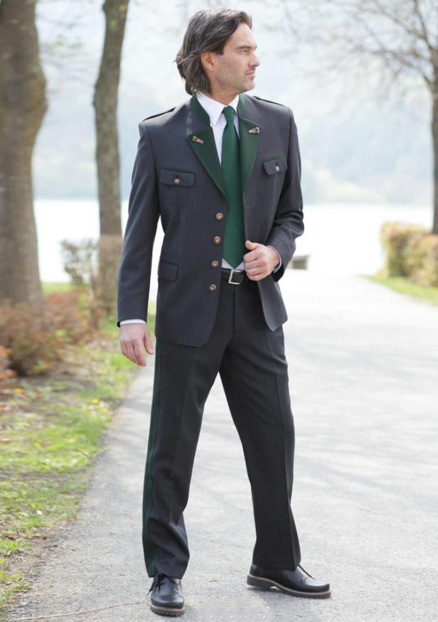 Ein Mann in Tracht steht auf einem Weg in der Natur.