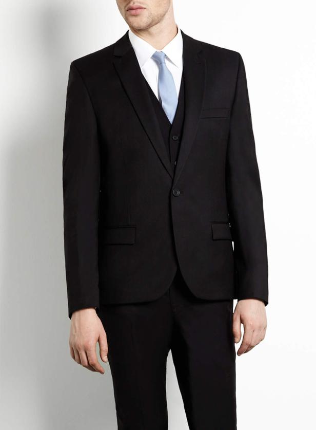 Ein Mann trägt einen schwarzen Anzug mit Weste und hellblauer Krawatte.