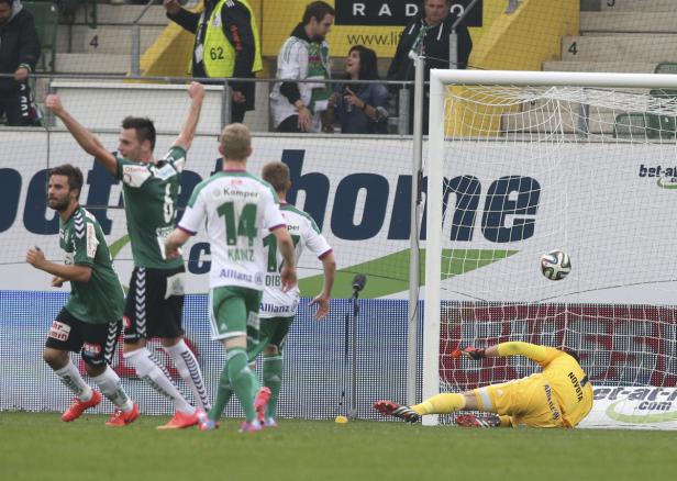 Ein Fußballspiel: Spieler jubeln, während der Torwart den Ball nicht abwehren kann.