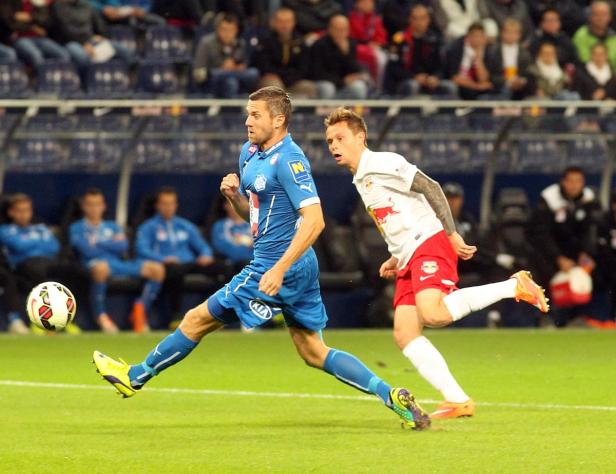 Zwei Fußballspieler kämpfen um den Ball auf dem Spielfeld.