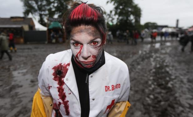 Eine als Zombie verkleidete Frau mit roter Kontaktlinse und blutverschmierter Arztkleidung.