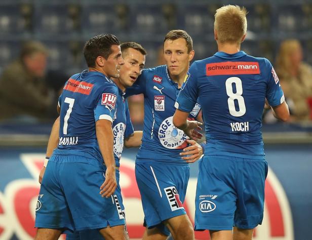 Eine Gruppe Fußballspieler in blauen Trikots feiert auf dem Spielfeld.