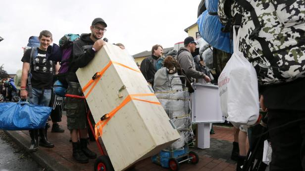 Menschen transportieren Gepäck und einen großen Holzkasten auf Rollwagen.
