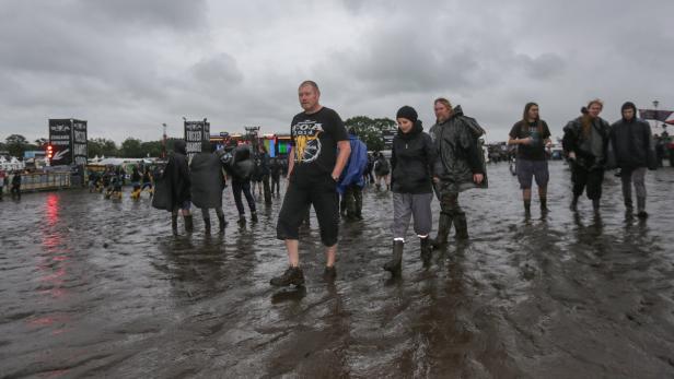 Besucher waten durch den Schlamm auf dem Wacken Open Air Festival.