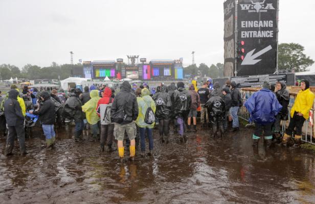 Besucher des Wacken Open Air Festivals waten durch den Schlamm.