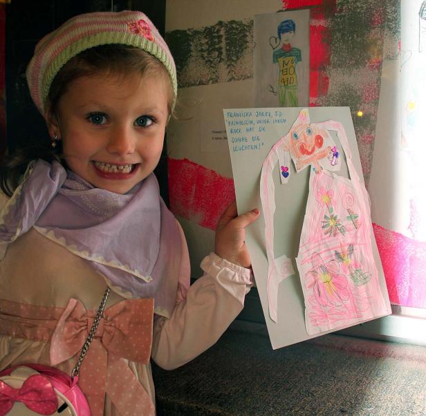 Ein kleines Mädchen präsentiert stolz eine Zeichnung von sich selbst als Prinzessin.