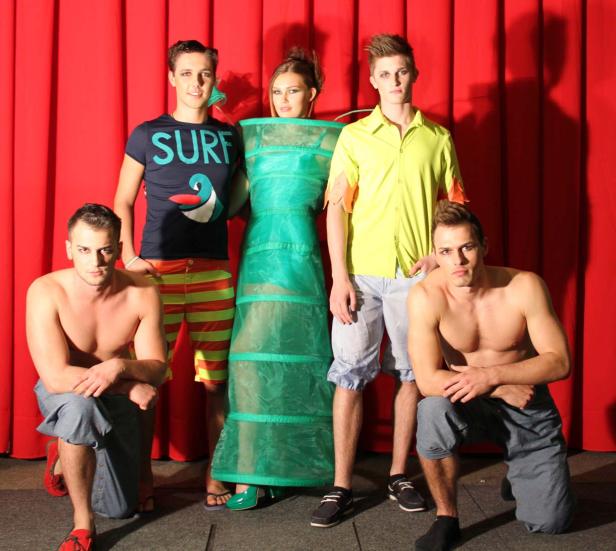 Fünf Models präsentieren ausgefallene Mode vor einem roten Vorhang.