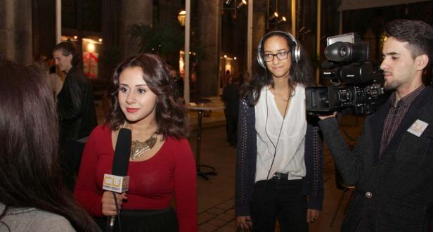 Eine Reporterin interviewt eine Person, während ein Kameramann die Szene filmt.