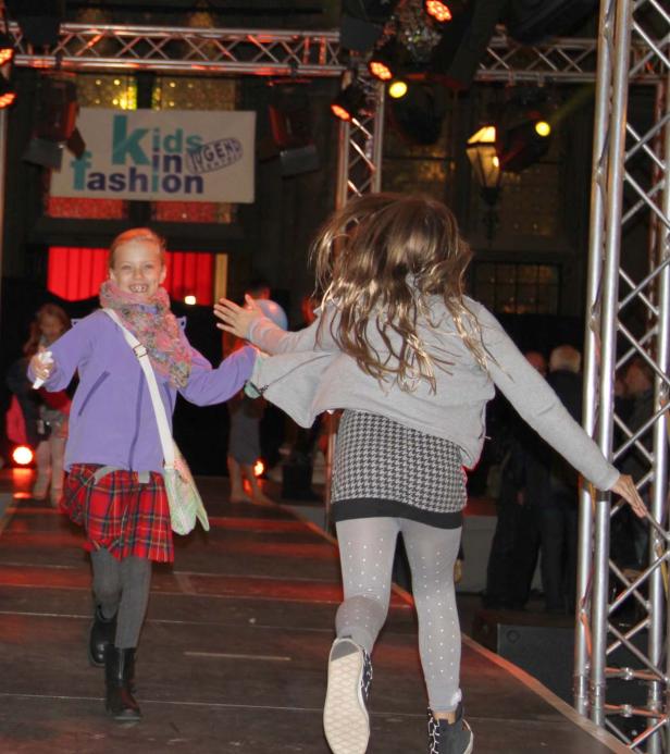 Zwei Mädchen laufen auf einer Bühne bei einer „Kids in Fashion“-Veranstaltung.