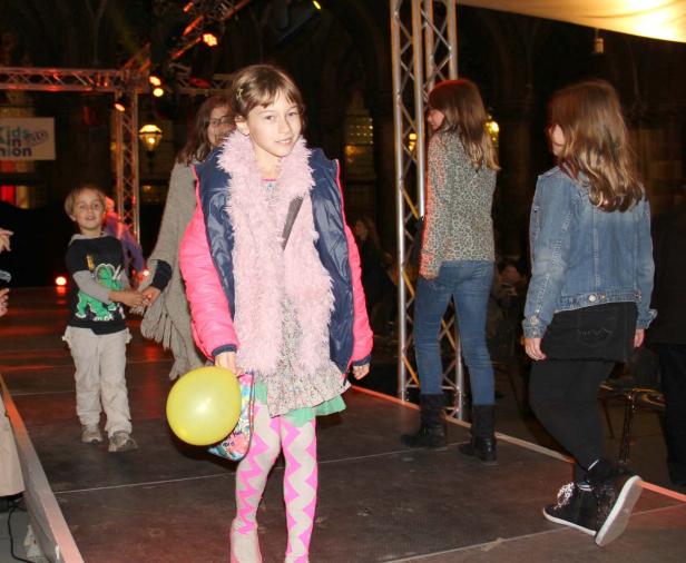 Ein junges Mädchen mit Ballon auf einer Bühne bei einer Modenschau.