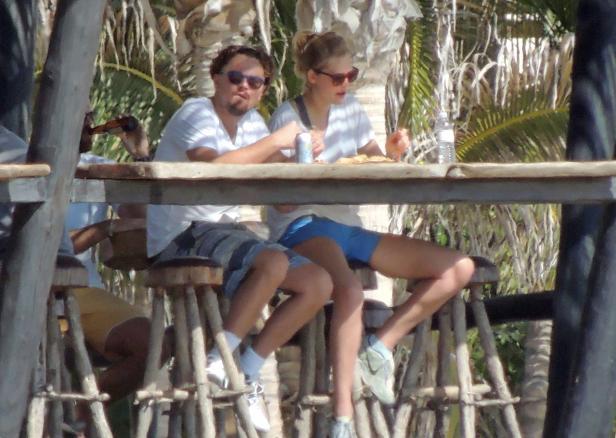 Leonardo DiCaprio und eine Frau sitzen an einem Tisch im Freien und essen Pizza.