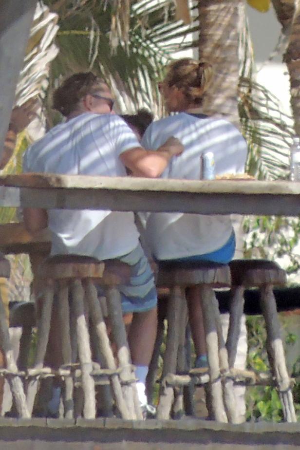 Zwei Personen sitzen an einem Tisch im Freien auf Barhockern.