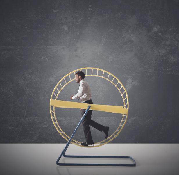 Ein Mann im Anzug rennt in einem Hamsterrad.