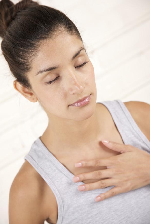 Eine Frau mit geschlossenen Augen legt ihre Hand auf ihre Brust.