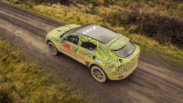 Ein mit Tarnmuster beklebter Aston Martin DBX auf einer schlammigen Straße.