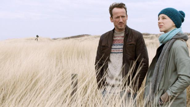 Ein Mann und eine Frau stehen in einem Feld mit hohem Gras.