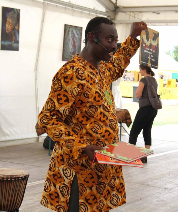 Ein Mann in einem gemusterten Hemd präsentiert ein Buch mit dem Titel „Die Großmutter über nimmt das Fernsehen“.