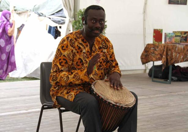 Ein Mann mit einem gemusterten Hemd spielt auf einer Trommel.