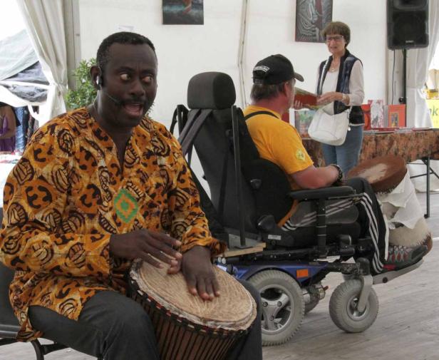 Ein Mann mit einem gemusterten Hemd spielt auf einer Djembe.