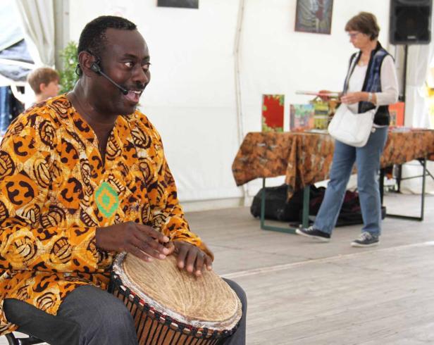 Ein Mann mit Headset spielt auf einer Djembe-Trommel.