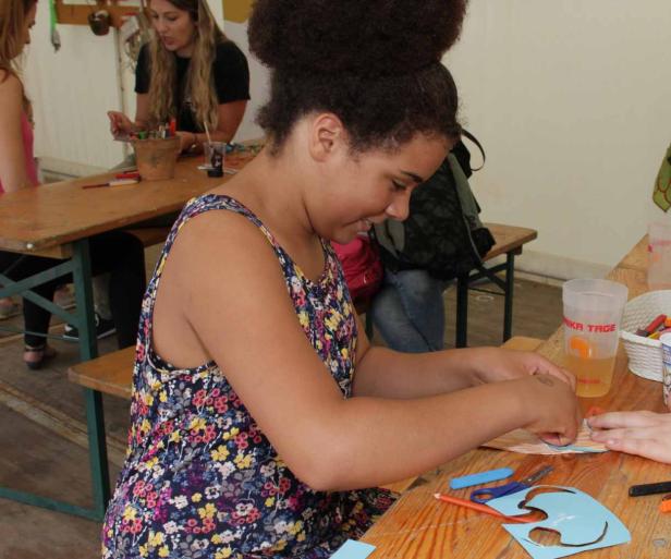 Eine junge Frau bastelt an einem Tisch mit Papier und Schere.