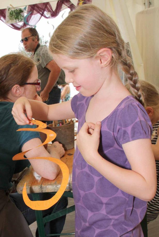 Ein Mädchen betrachtet eine orangefarbene Papiergirlande.