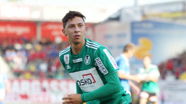 Ein junger Fußballspieler in einem grün-weißen Trikot auf dem Spielfeld.