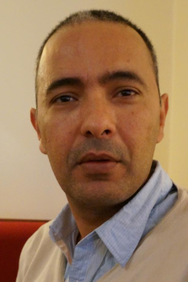 Porträt eines Mannes mit hellblauem Hemd und beigem Pullover.