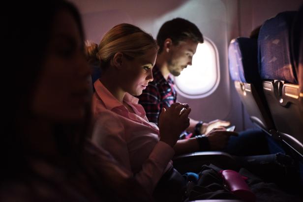 Woman using smart phone in airplane.
