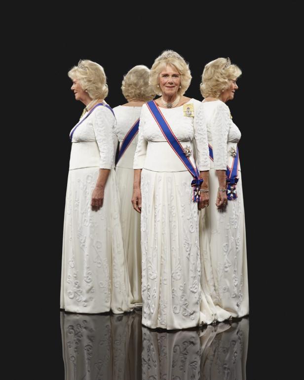 Ein Porträt von Königin Camilla in einem weißen Kleid mit Schärpe und Tiara, umgeben von Spiegelbildern.