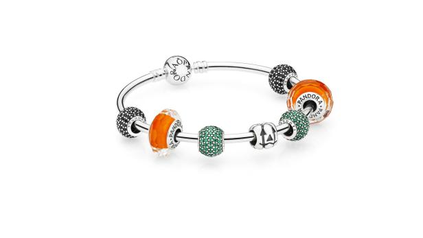 Ein silbernes Pandora-Armband mit orangefarbenen, grünen und schwarzen Charms.