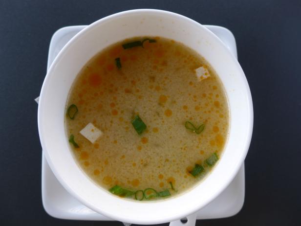 Eine Schüssel Misosuppe mit Tofu und Frühlingszwiebeln.