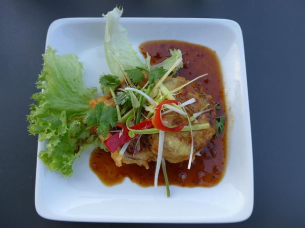 Ein Gericht mit Salat, Gemüse und einer dunklen Soße auf einem weißen Teller.