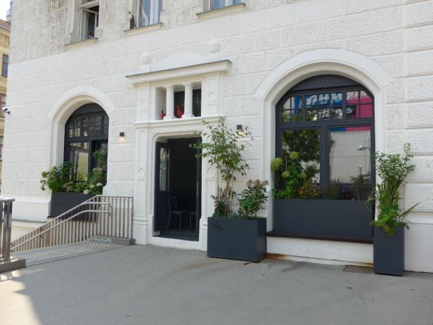 Die Fassade eines Gebäudes mit Eingangstür und bepflanzten Fenstern.