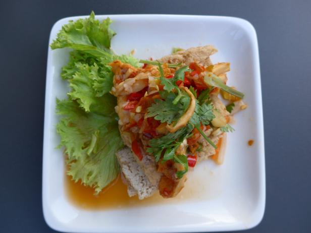 Ein Teller mit Tofu-Salat, garniert mit Salatblättern und Koriander.