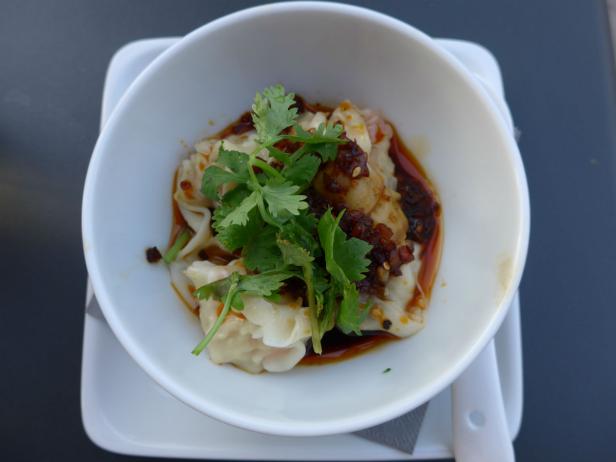 Eine Schüssel mit asiatischen Teigtaschen, garniert mit Koriander und Chiliöl.