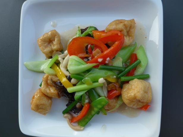 Gebratener Tofu mit Gemüse auf einem weißen Teller.
