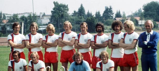 Eine Fußballmannschaft posiert für ein Gruppenfoto auf einem Rasenplatz.