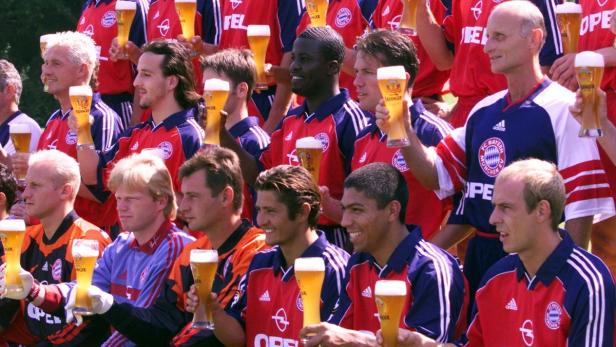 Eine Gruppe von Fußballspielern des FC Bayern München hält Biergläser in die Höhe.