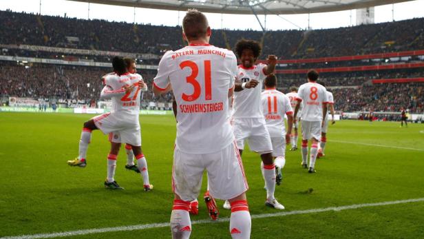 Fußballspieler von Bayern München feiern auf dem Rasen.