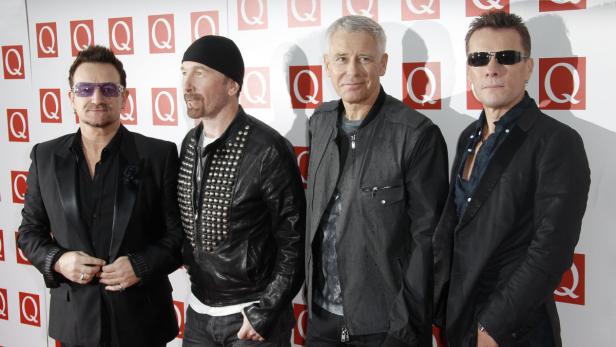 Die Band U2 posiert vor einer Wand mit dem „Q“-Logo.
