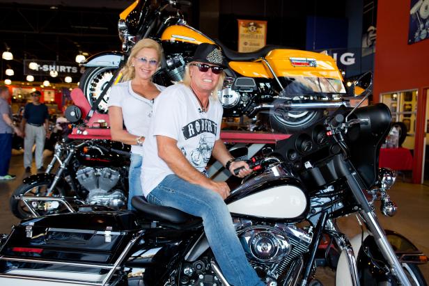 Ein Mann und eine Frau posieren auf und hinter zwei Harley-Davidson-Motorrädern.